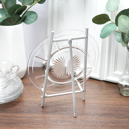 Satin silver metal easel displaying a clear glass plate on wooden surface