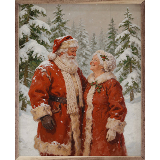 Framed painting of Santa and Mrs. Claus in snowy pine forest, red coats