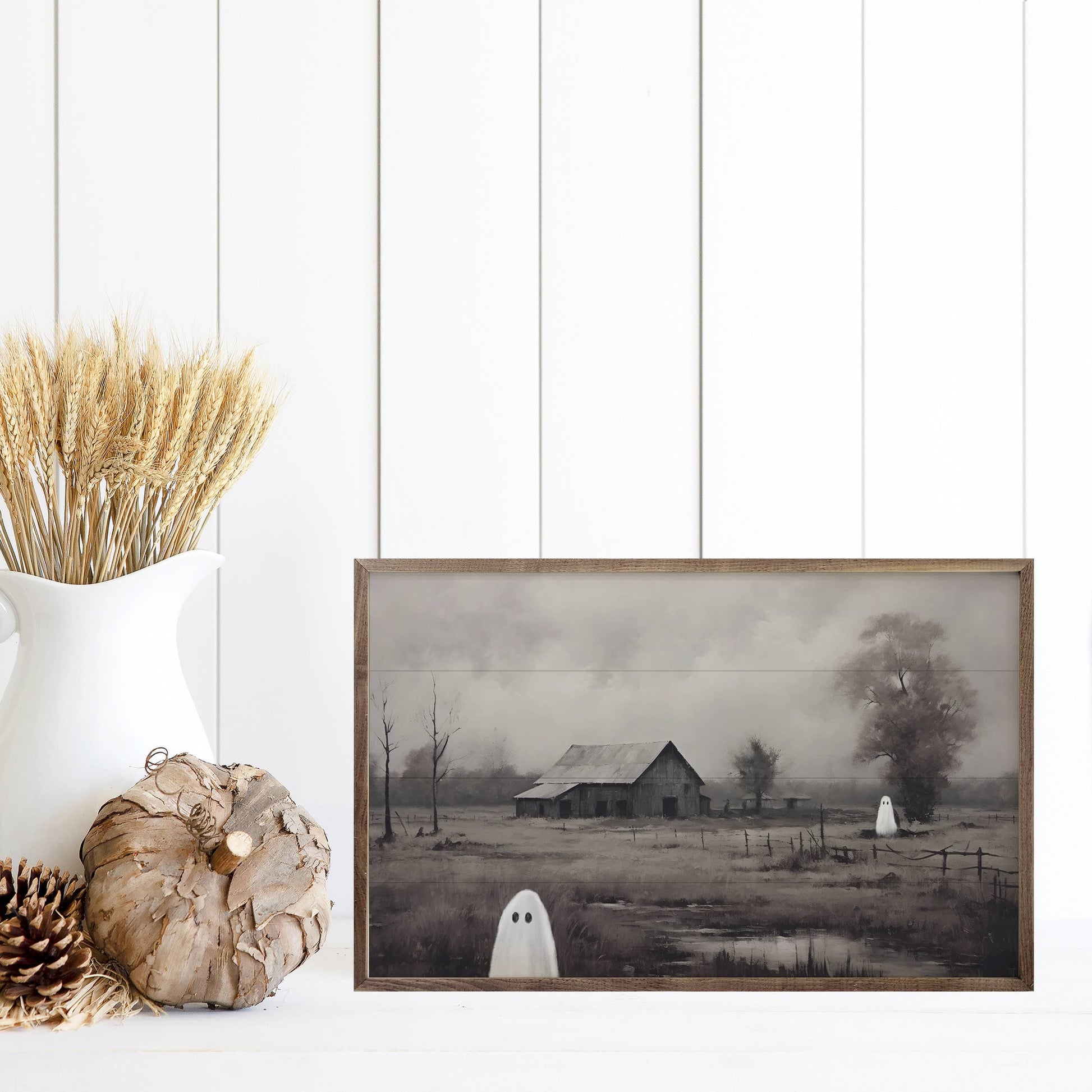 Framed Halloween barn and ghost painting displayed with wheat stems and rustic pumpkin decor