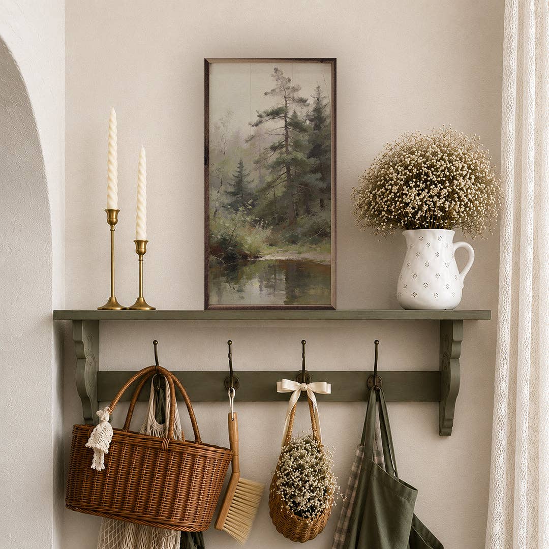 Framed misty pine forest painting displayed on sage green wall shelf with decor