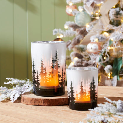 Frosted glass candle holders with pine tree silhouette design, glowing amber light, two sizes