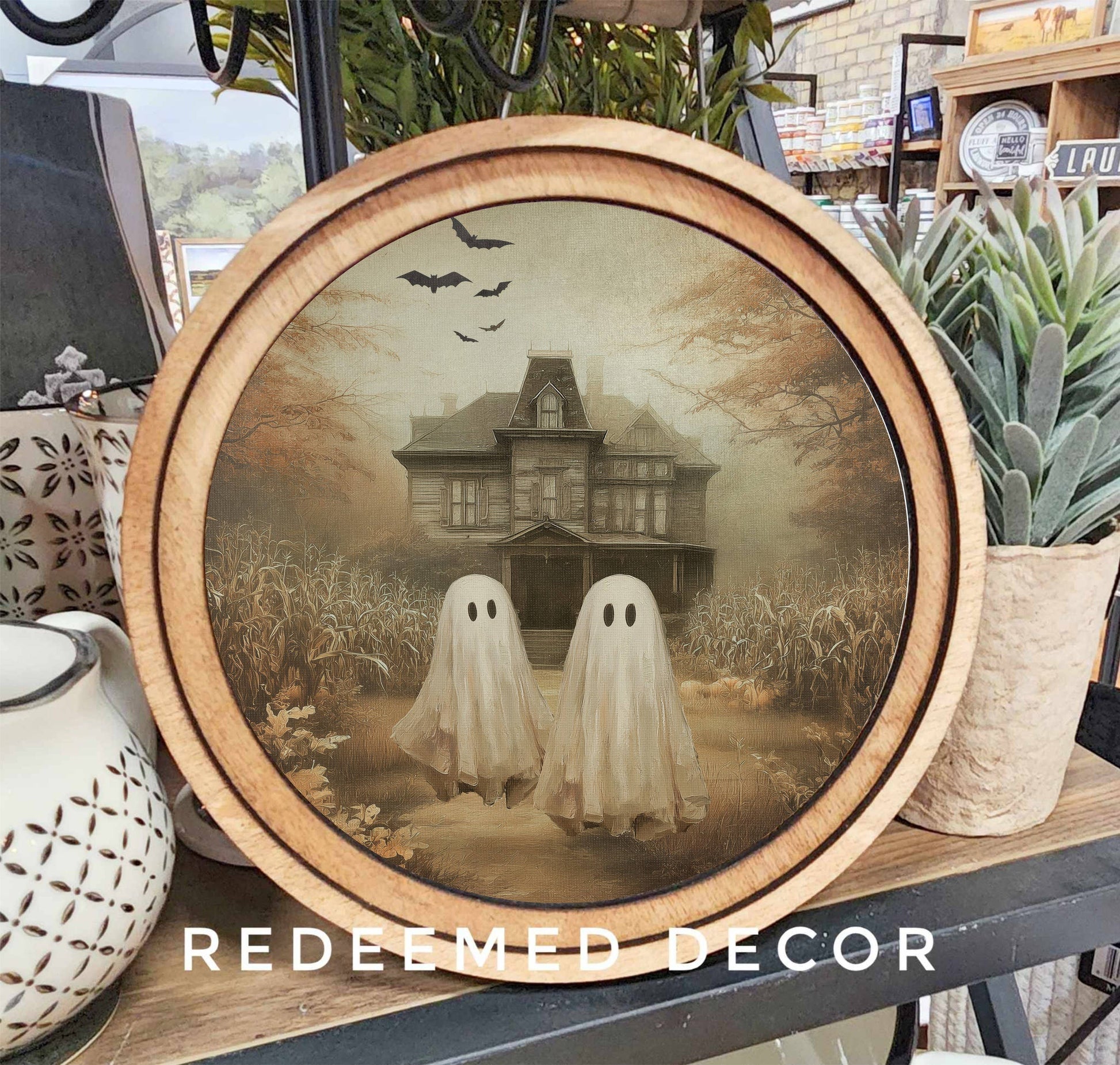 Round wood-framed canvas wall art with two ghosts and haunted mansion scene