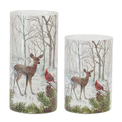 Two glass cylinder candle holders with painted woodland deer, cardinals, and snowy trees