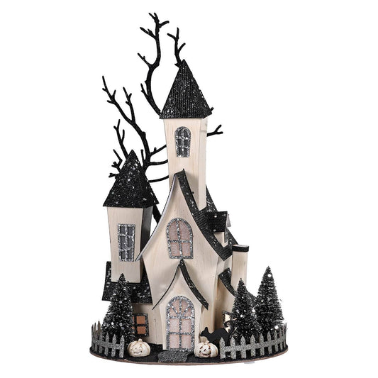 Cardboard haunted house decoration with black glitter roofs, bare trees, miniature pumpkins, and fence