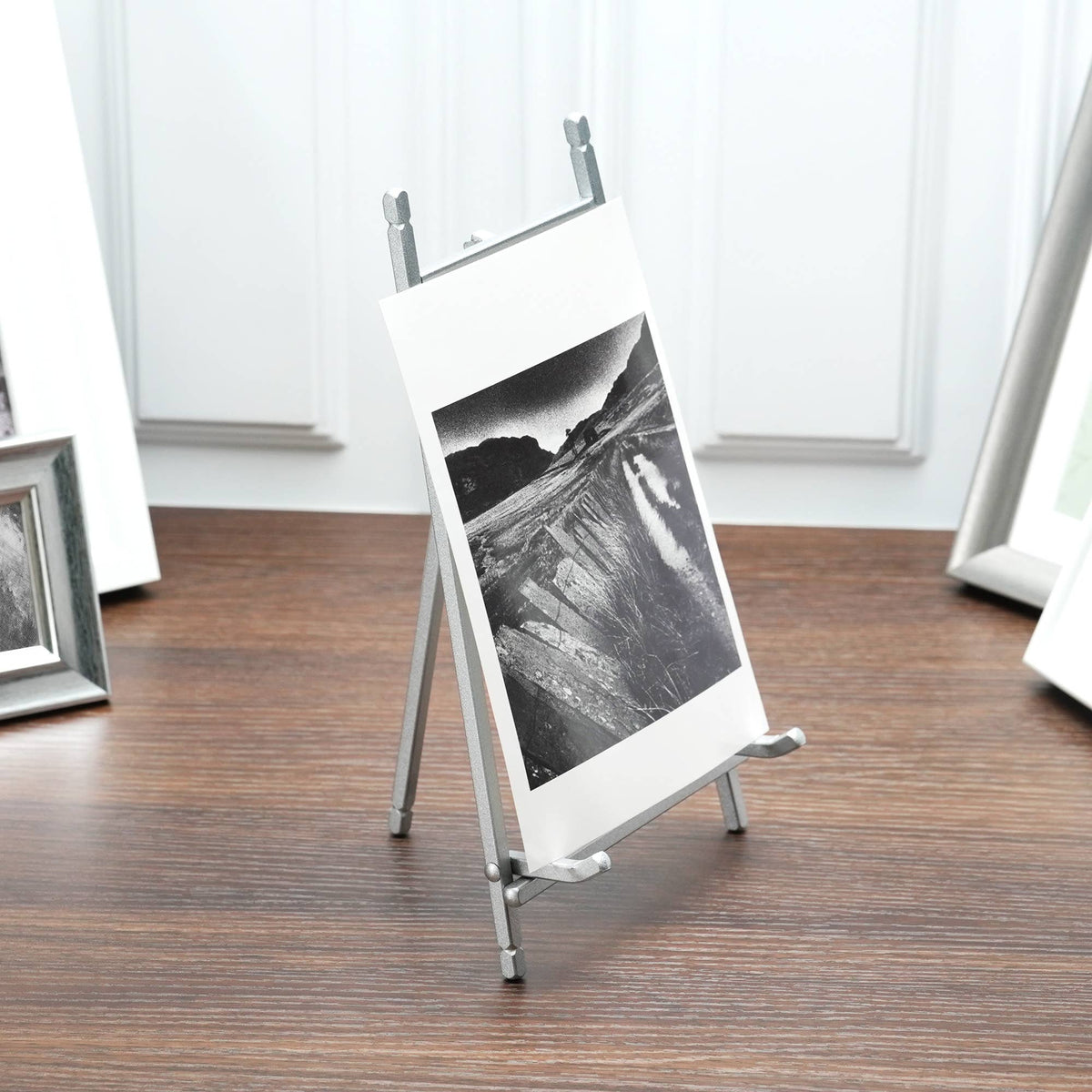 Satin silver metal easel displaying a black and white landscape photo on wood floor