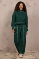 Pine green barrel pants with ivory contrast stitching, relaxed tapered fit