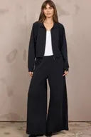 Black wide-leg pleated pants with matching black zip-up bomber jacket outfit