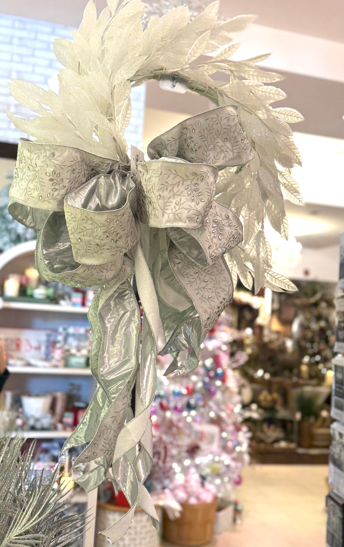Large silver beaded bow with embossed leaf ribbon on white decorative wreath