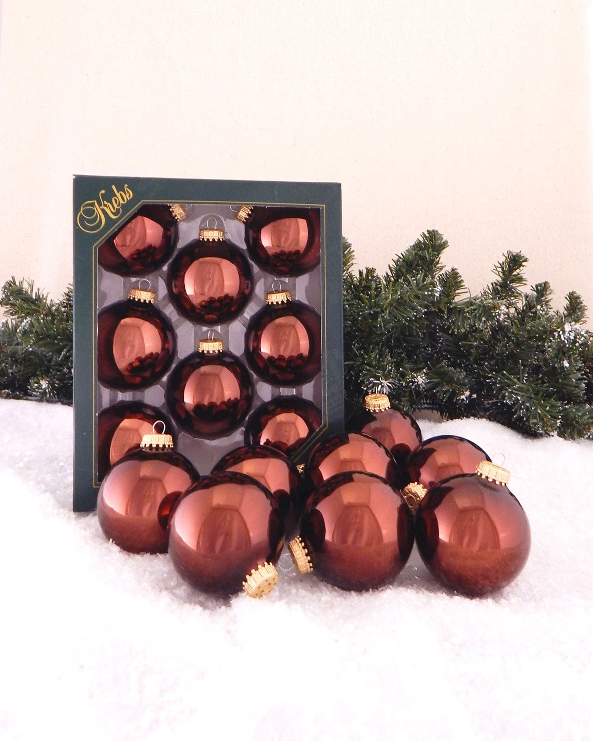 Shiny deep brown glass ball ornaments with gold caps, displayed in box and loose on snow