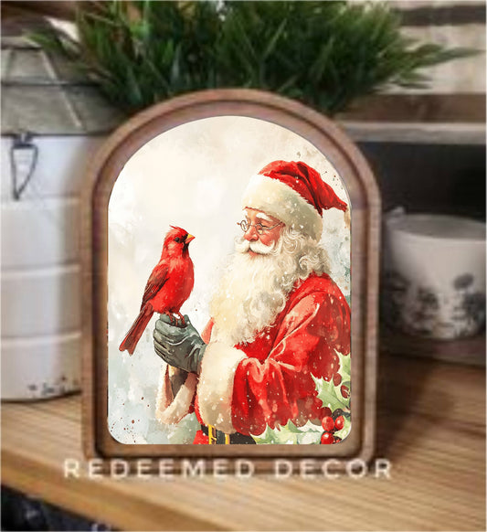 Arch-framed Santa Claus holding a red cardinal, wood frame, shelf decor