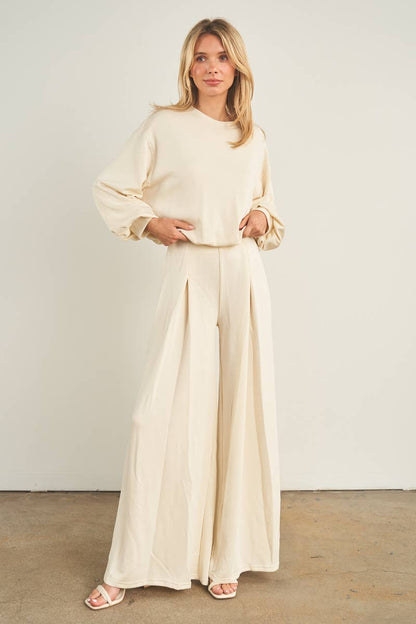 Cream wide-leg palazzo pants with pleated front, paired with matching long-sleeve top
