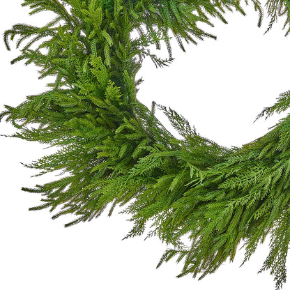 Close-up of a lush green cedar and Norfolk pine wreath with feathery branches on white background