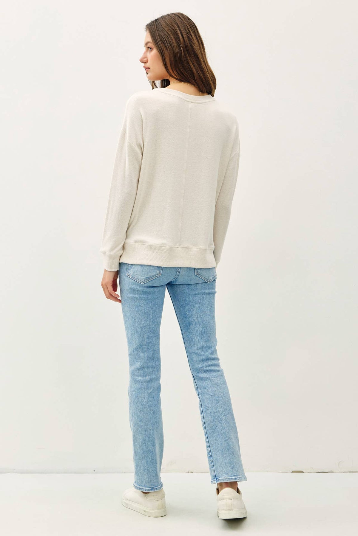 Cream long-sleeve brushed pullover knit top paired with light wash straight jeans
