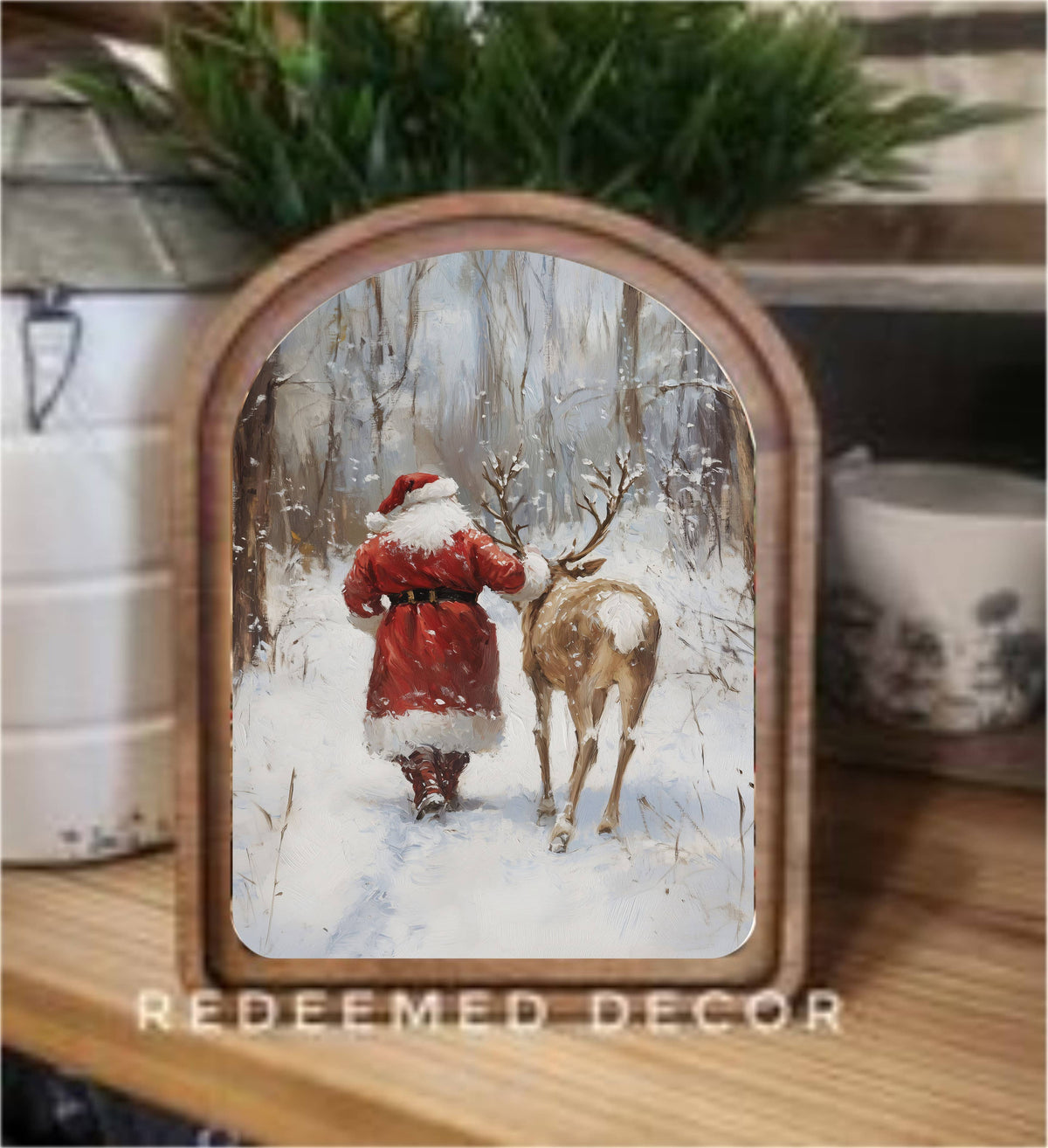 Arched wood-framed canvas art of Santa and reindeer walking in snowy winter forest