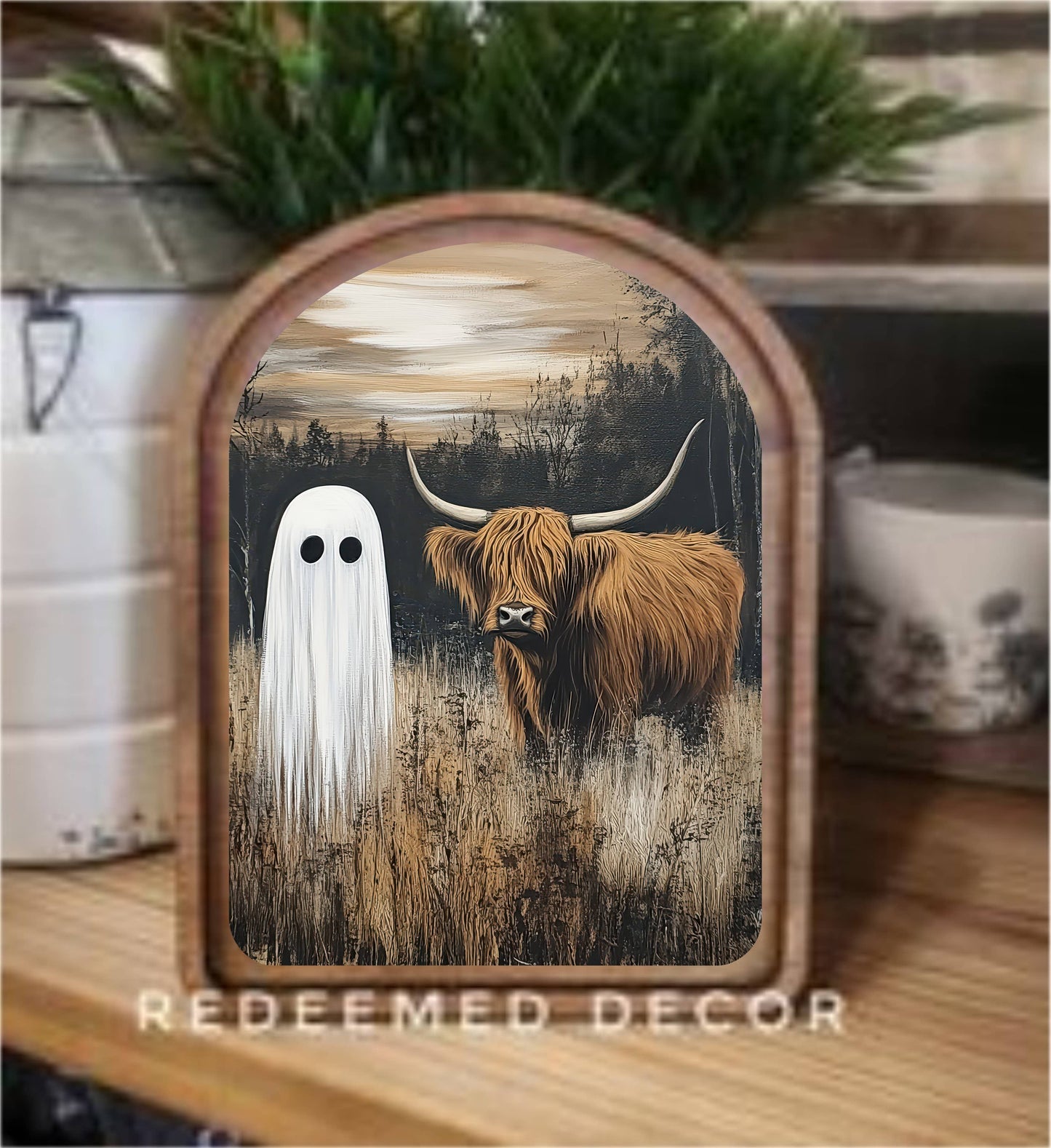 Arched wood-framed canvas art featuring a ghost and Highland cow in a dark moody field