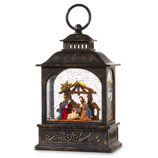 Antique bronze lantern with glass panels enclosing a lit nativity scene and swirling glitter