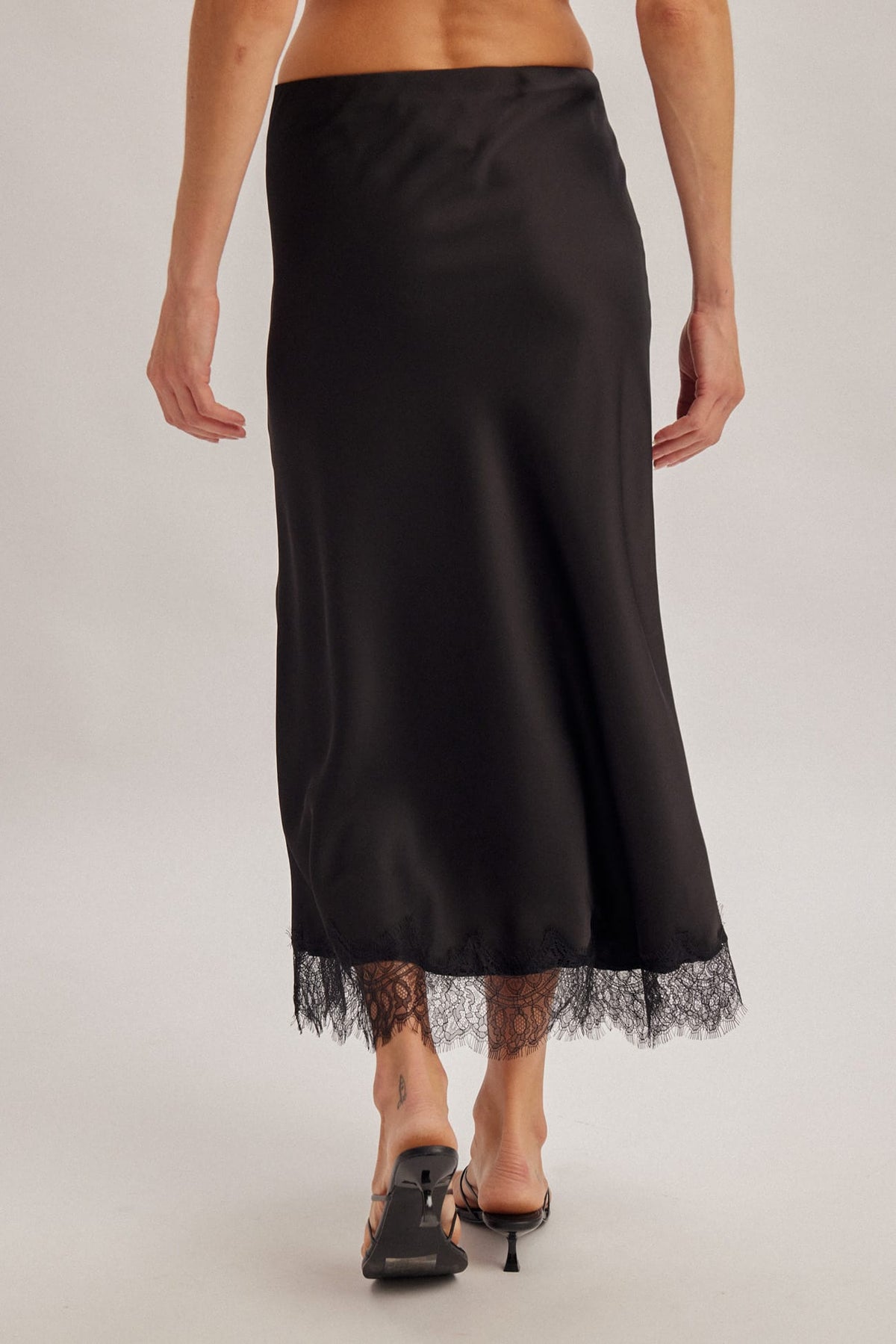 Black satin midi skirt with delicate lace trim hem, back view