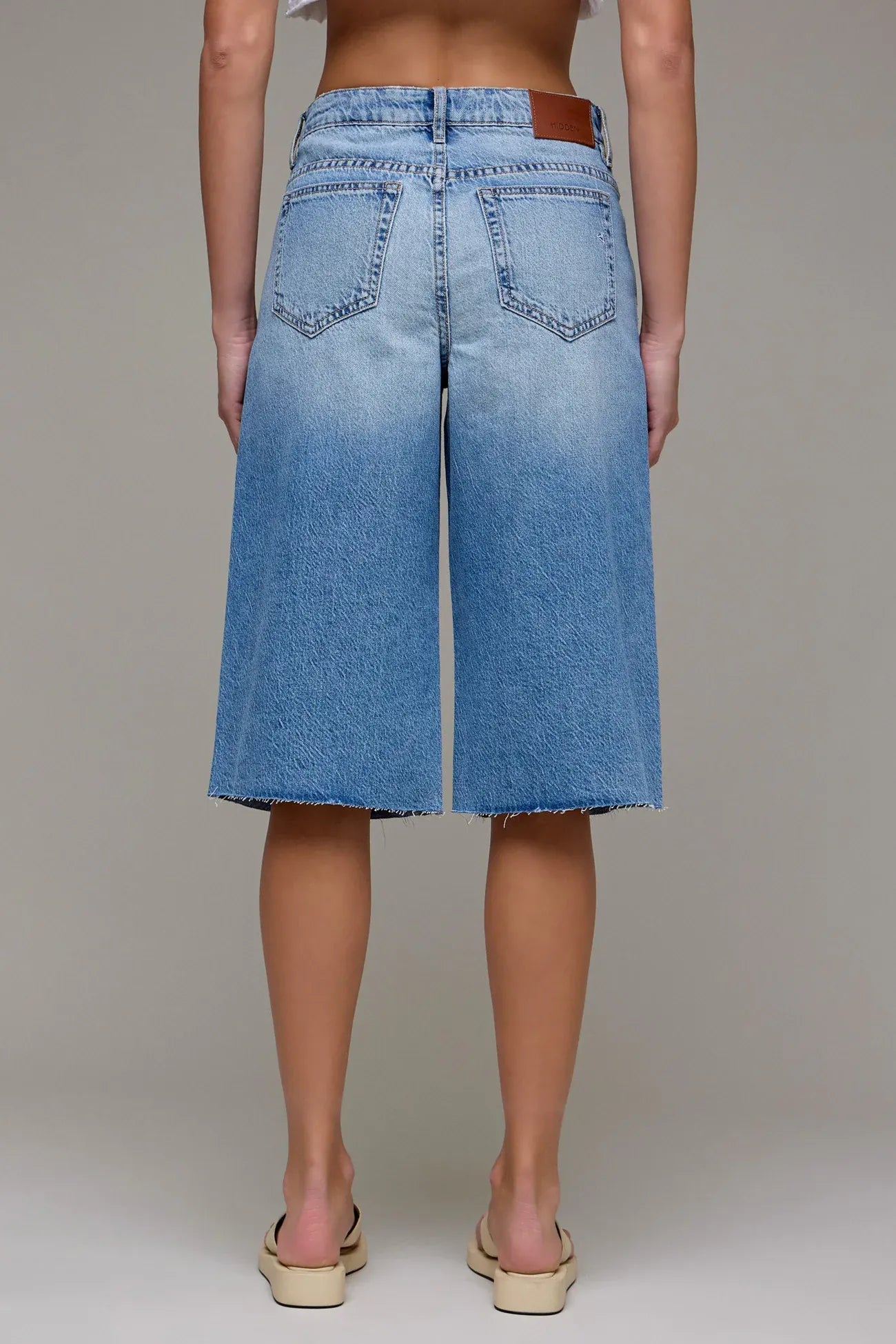 Light blue wide-leg denim bermuda shorts with raw hem, back view