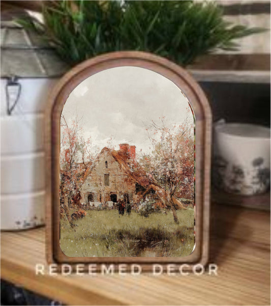 Arch top wood framed canvas art depicting a vintage French cottage with autumn trees