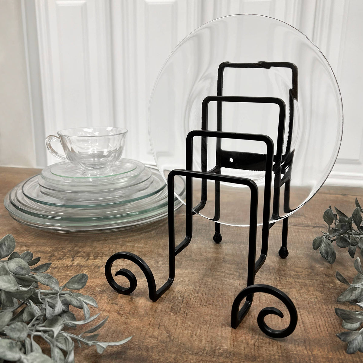 Black wrought iron 4-slot plate display stand holding a clear glass plate