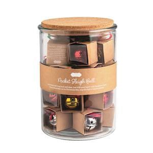 Glass jar with cork lid filled with miniature metallic sleigh bells in assorted colors
