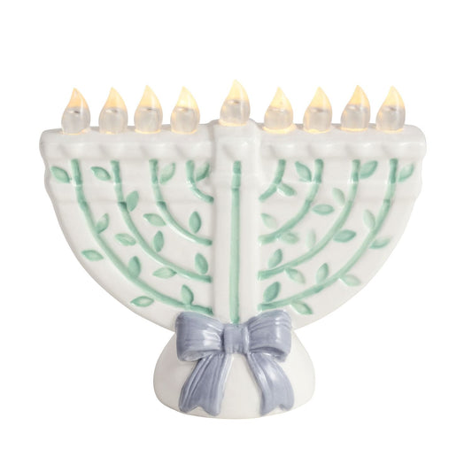 White ceramic LED menorah with green vine details and blue bow, all nine lights glowing