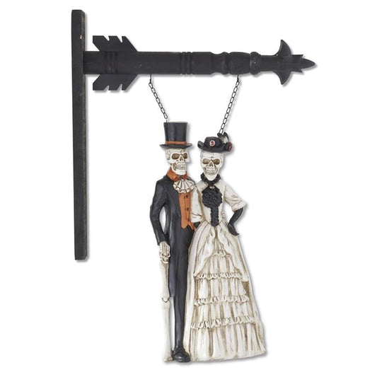 Resin skeleton couple in formal Victorian attire hanging from black arrow bracket