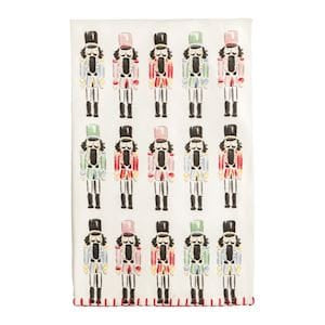 White kitchen towel with rows of colorful nutcracker soldiers in pink, red, and green