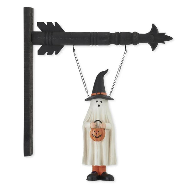 White ghost figure in black witch hat holding pumpkin hanging from black arrow sign bracket