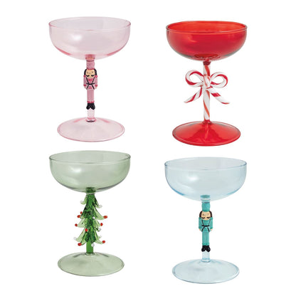 Four festive Christmas coupe glasses in pink, red, green, and blue with holiday figural stems