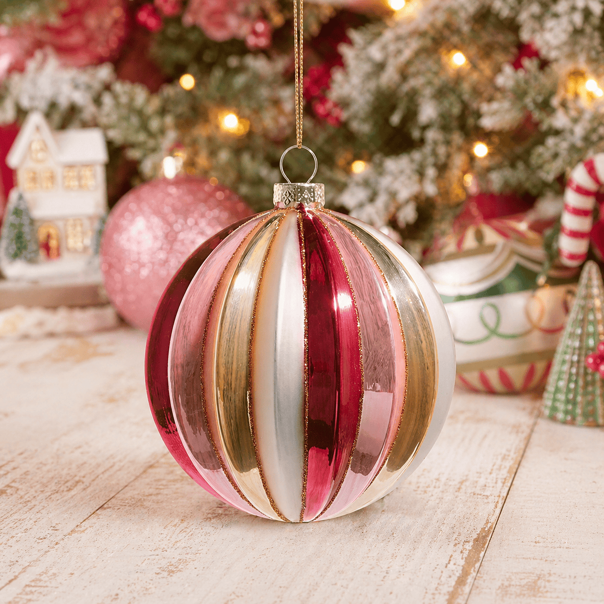 Ribbed glass ball ornament with pink, magenta, gold, and white vertical stripes, hanging display