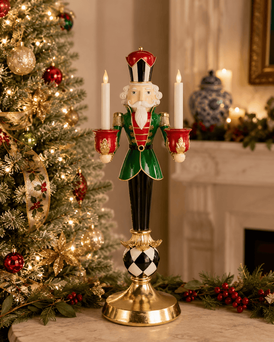 Nutcracker candle holder with two white candles, green coat, red hat, and black-and-white harlequin ball base