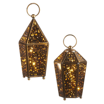 Two antiqued glass lanterns with gold speckled pattern and brass ring handles lit from within