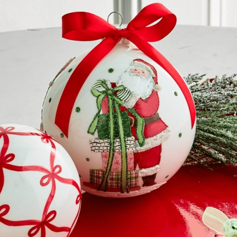 Large white ball ornament with Santa holding gifts, red satin bow on top, front view