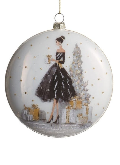 Glass disc ornament featuring elegant woman in black gown with Christmas tree and gifts