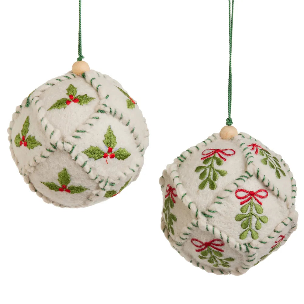 Two ivory felt ball ornaments embroidered with holly and mistletoe in green and red