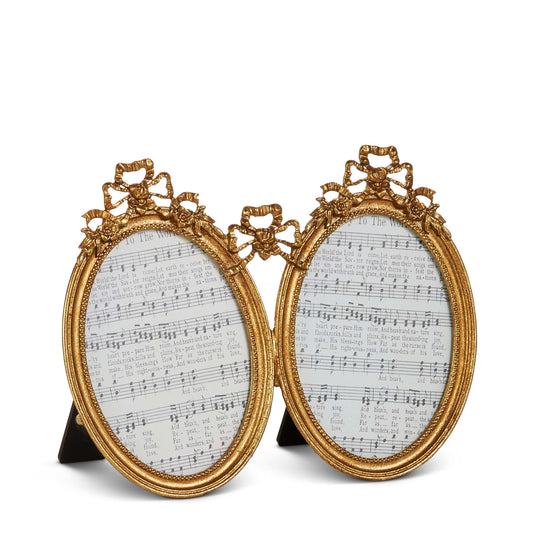 Pair of ornate gold oval picture frames with decorative bow and floral embellishments, displaying sheet music