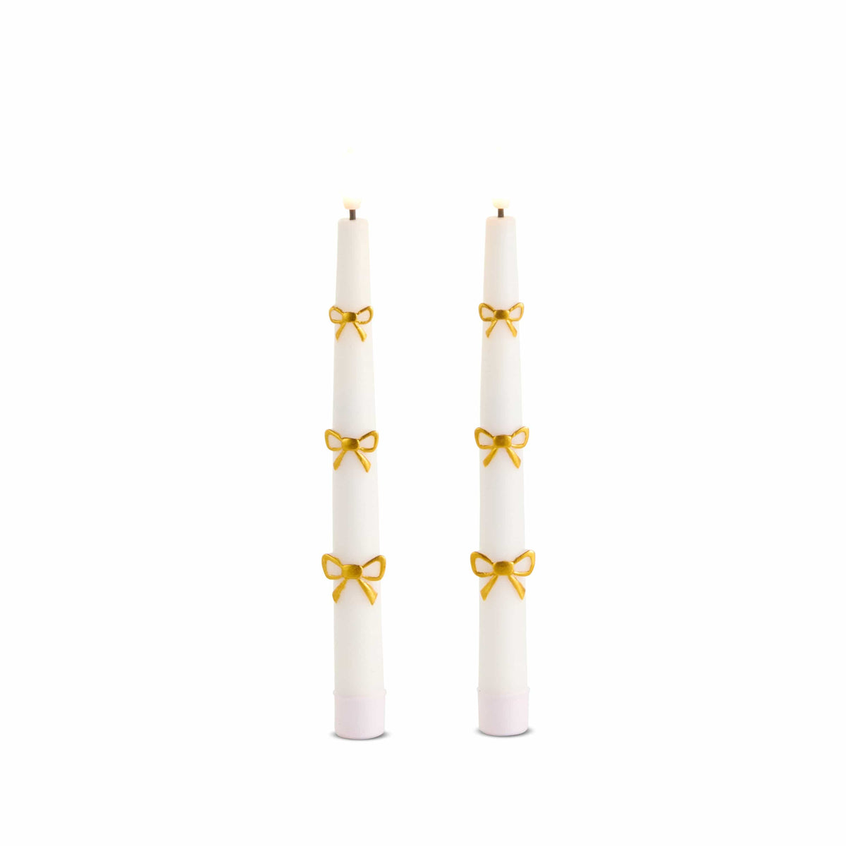 Pair of white taper candles with three gold embossed bow decorations each, lit wicks