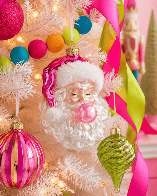 Glass Santa Claus face ornament blowing a pink bubblegum bubble, with white beard and pink hat
