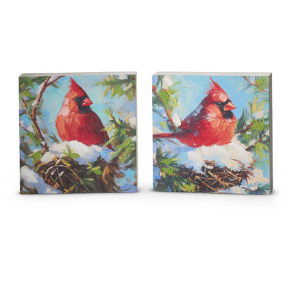 Two square decorative blocks featuring painted red cardinal birds perched on snowy nest branches