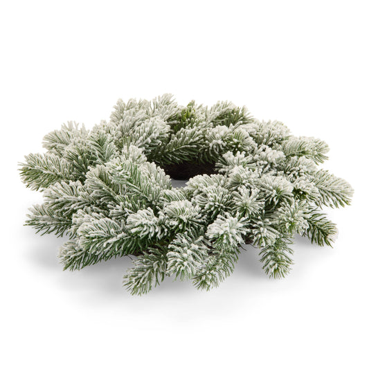 Snow-flocked pine needle wreath candle ring laid flat, viewed from slight angle