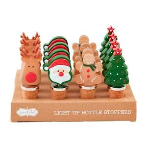 A set of four Christmas-themed light-up bottle stoppers displayed on their wooden retail base. The stoppers include a reindeer, Santa Claus, gingerbread men, and a Christmas tree, each with a cork base and colorful holiday designs.