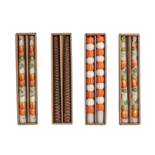 Four boxed fall taper candle sets with pumpkin, rattan, and vine patterns in orange and white