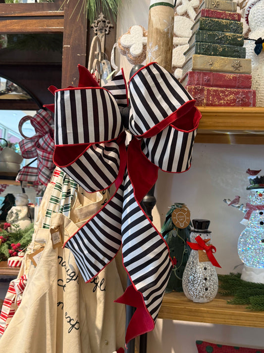 Oversized black and white striped Christmas bow with red velvet trim and long tails