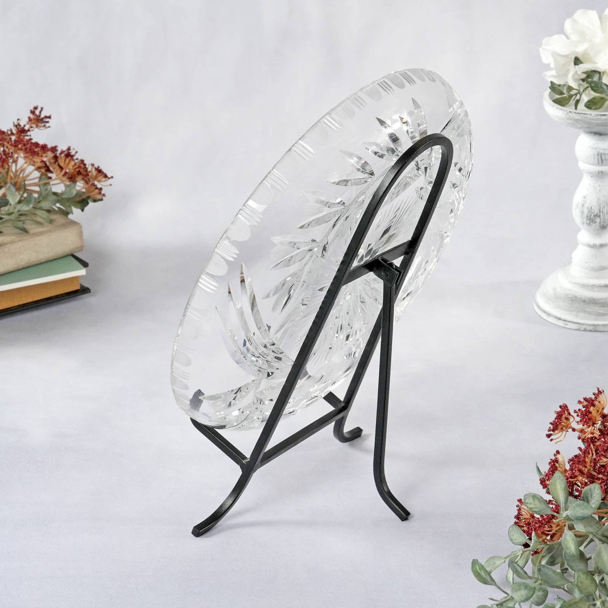 Black wrought iron easel displaying a cut crystal plate on white surface