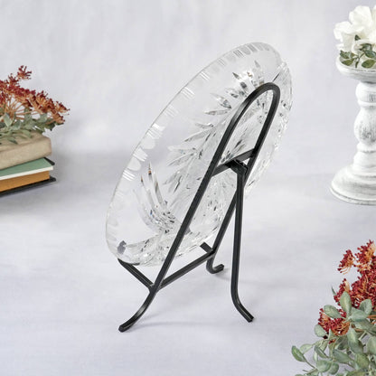 Black wrought iron easel displaying a cut crystal plate on white surface