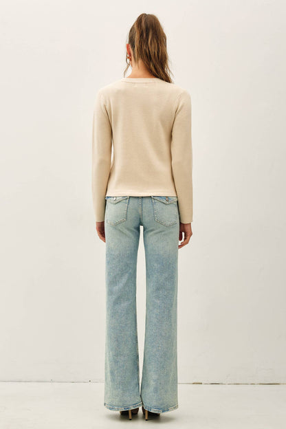 Beige long-sleeve crewneck cardigan with snap button closure, styled with wide-leg jeans