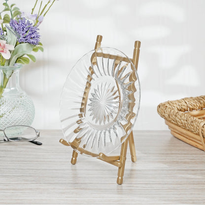 Gold satin metal easel displaying a clear cut-glass plate on a wooden surface