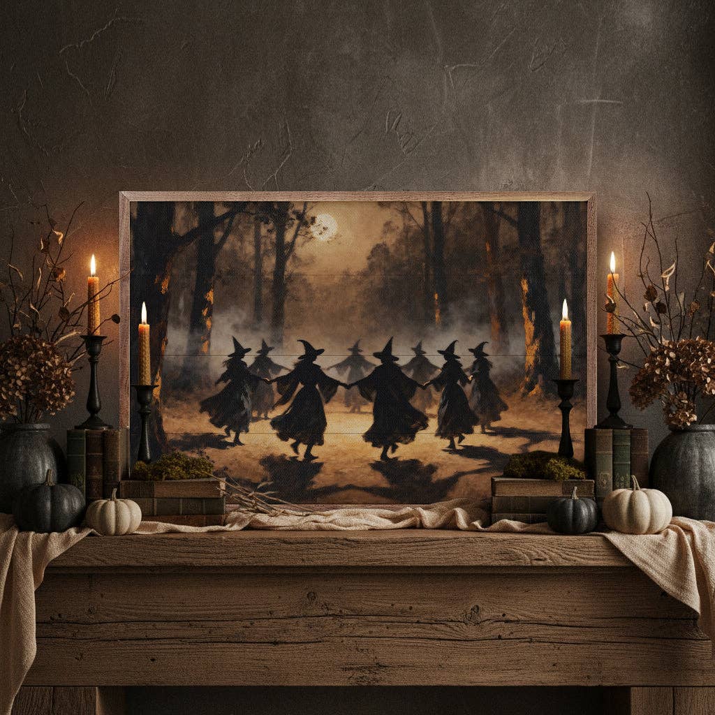 Framed canvas print of silhouetted witches dancing in moonlit forest on rustic mantel