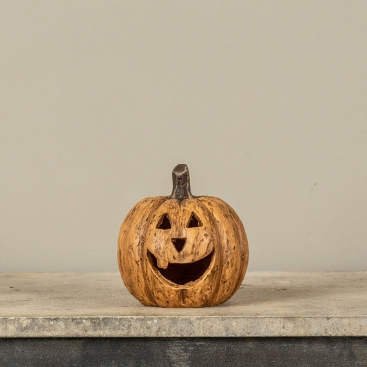 Rustic terracotta jack-o-lantern figurine with smiling carved face and dark stem